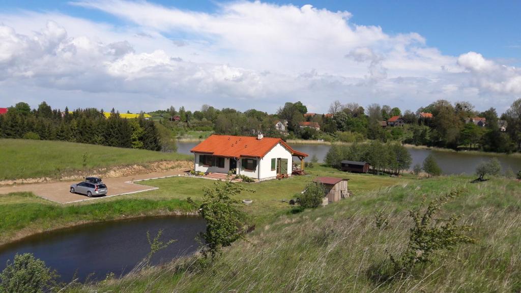 une maison avec un toit orange à côté d'un lac dans l'établissement Siedlisko Upałty, à Giżycko