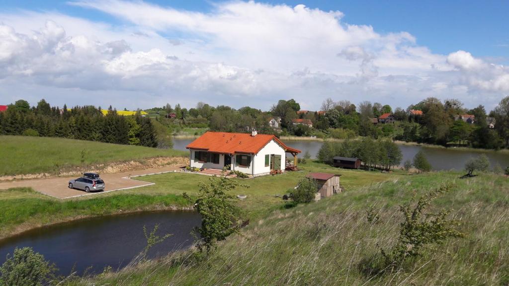 a house with an orange roof next to a lake at Siedlisko Upałty in Giżycko