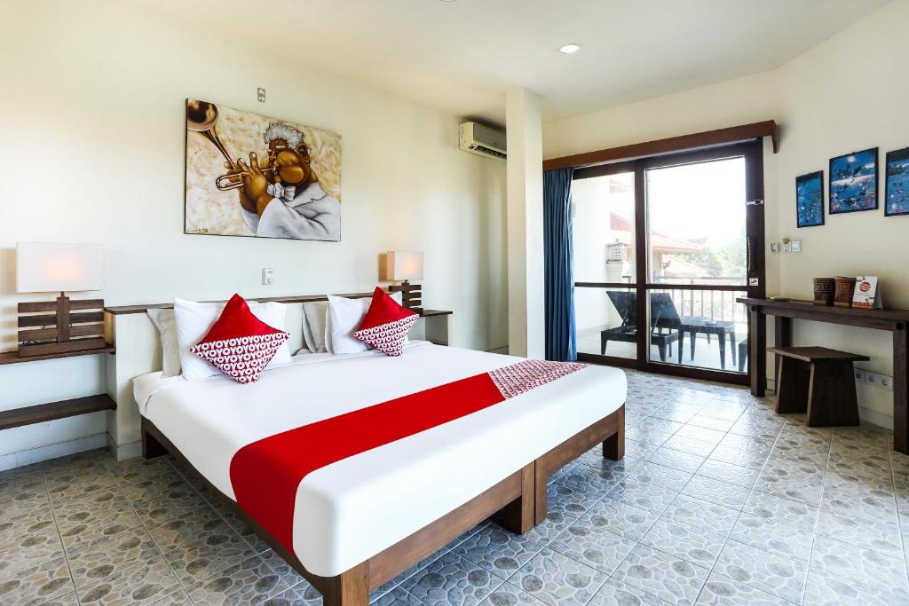 a bedroom with a large bed with red and white pillows at OYO 90893 Mimpi Bungalows in Kuta