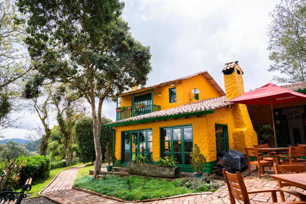 Casa amarilla con mesa y sillas en Estancia San Antonio en Guasca
