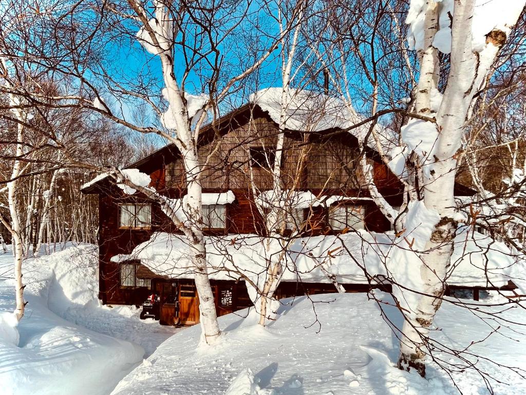 una casa cubierta de nieve en el bosque en Okushiga Lodge Yama no Manimani, en Yamanouchi