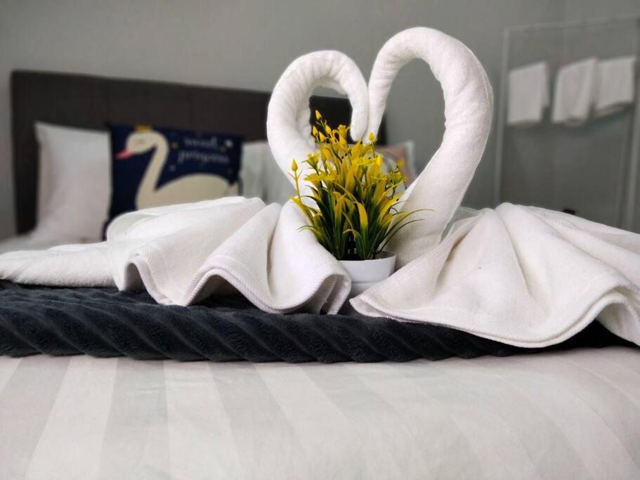 two swans towels and flowers on a bed at Homey 9pax 3BR MRT Cheras Tmn Suntex I HomeBrickz in Cheras