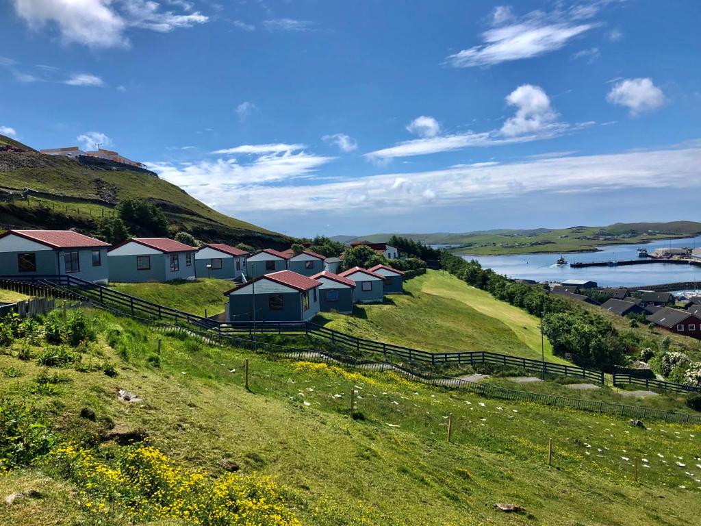 a row of houses on a hill next to a lake at Easterhoull Chalets in Scalloway
