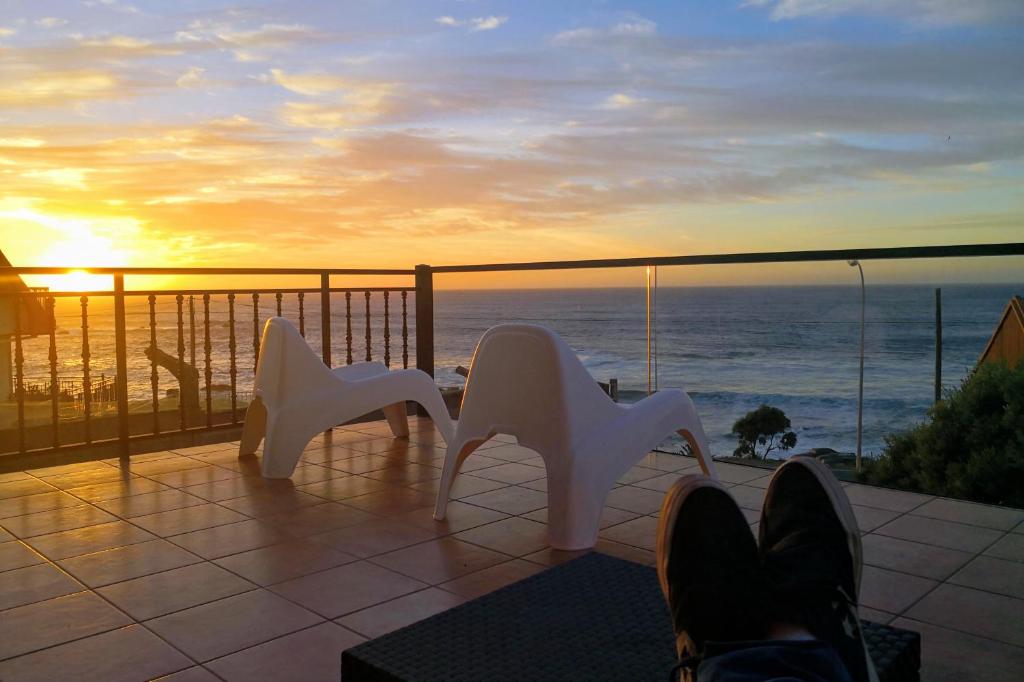 2 sillas blancas en un balcón con vistas al océano en Albergue da Costa en Muxía