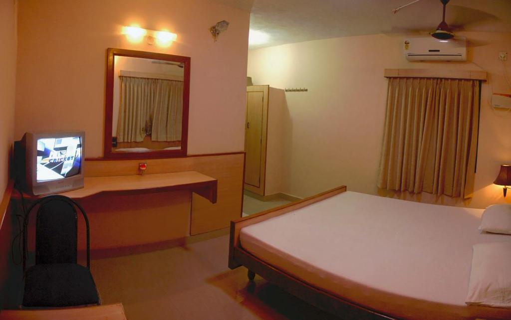 una camera con un letto e una televisione di Vinodhara Guest House a Mamallapuram