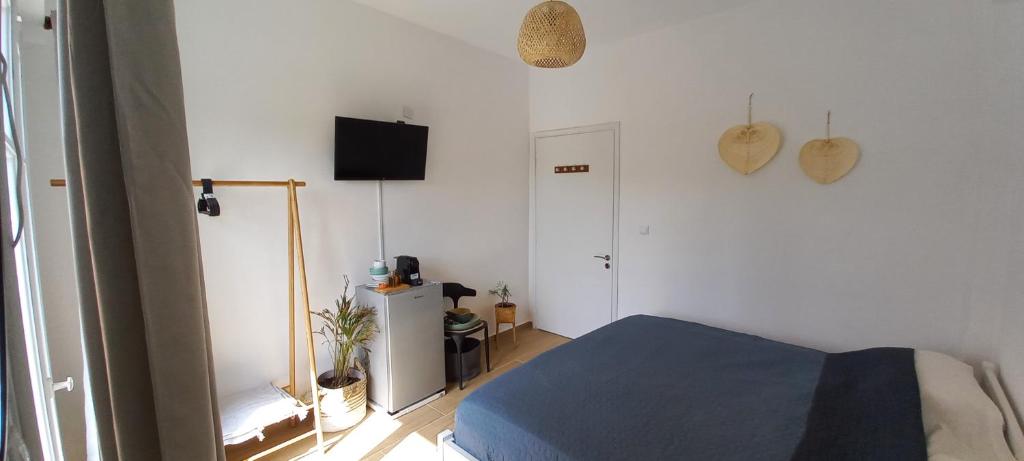 Un dormitorio con una cama azul y un televisor. en La Mandynia Studio, en Kato Korakiana