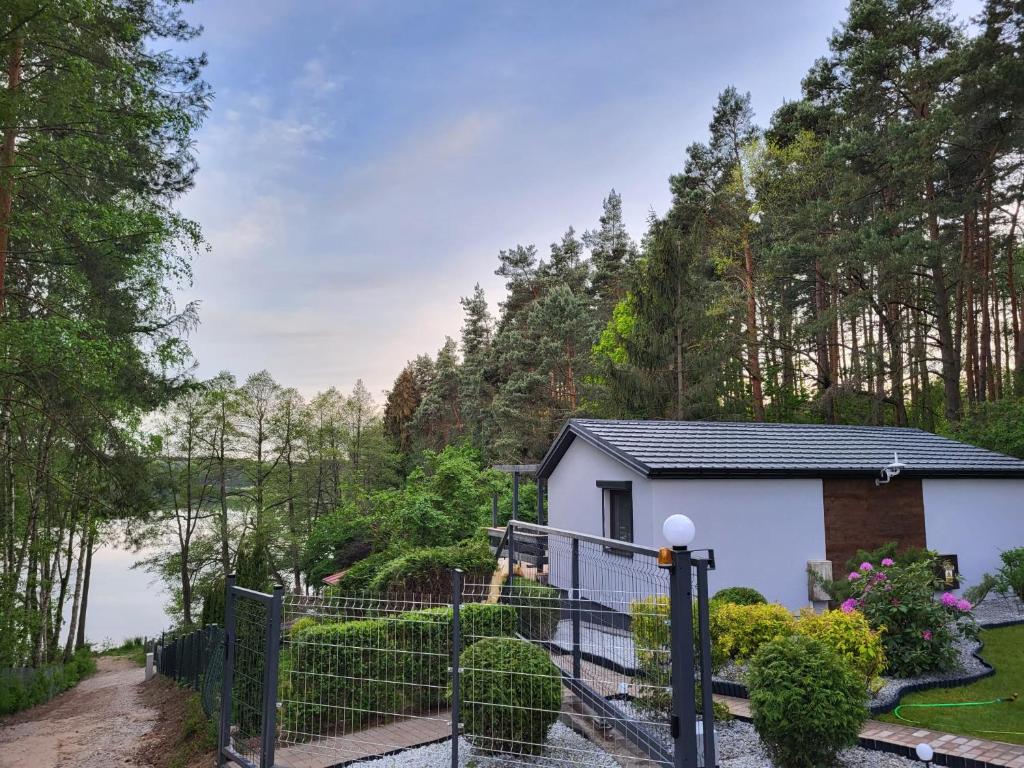 a white house with a fence next to a lake at Zacisze Huta in Huta