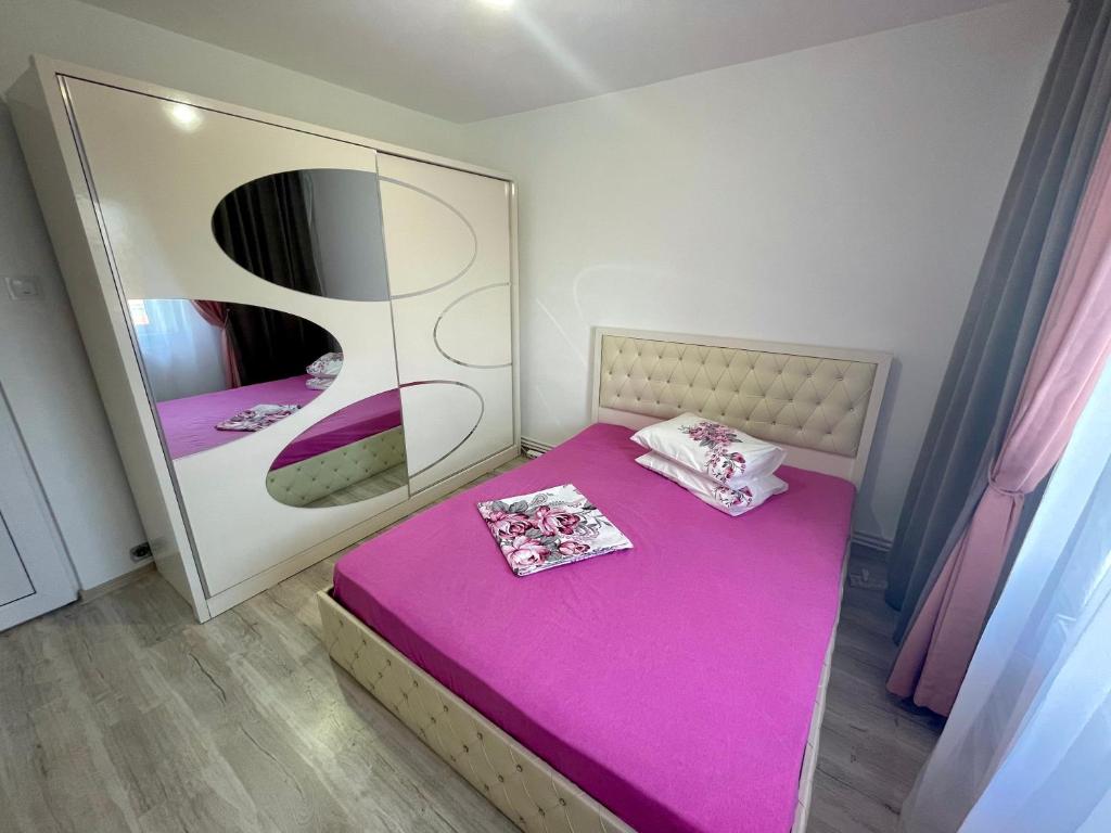 a small bedroom with a pink bed and a mirror at Residence RMZ in Mangalia