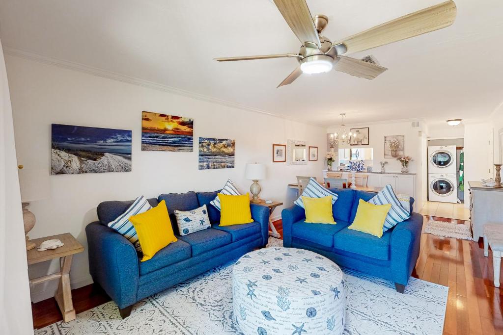 a living room with two blue couches and yellow pillows at Beach & Gulf Escape in Holmes Beach
