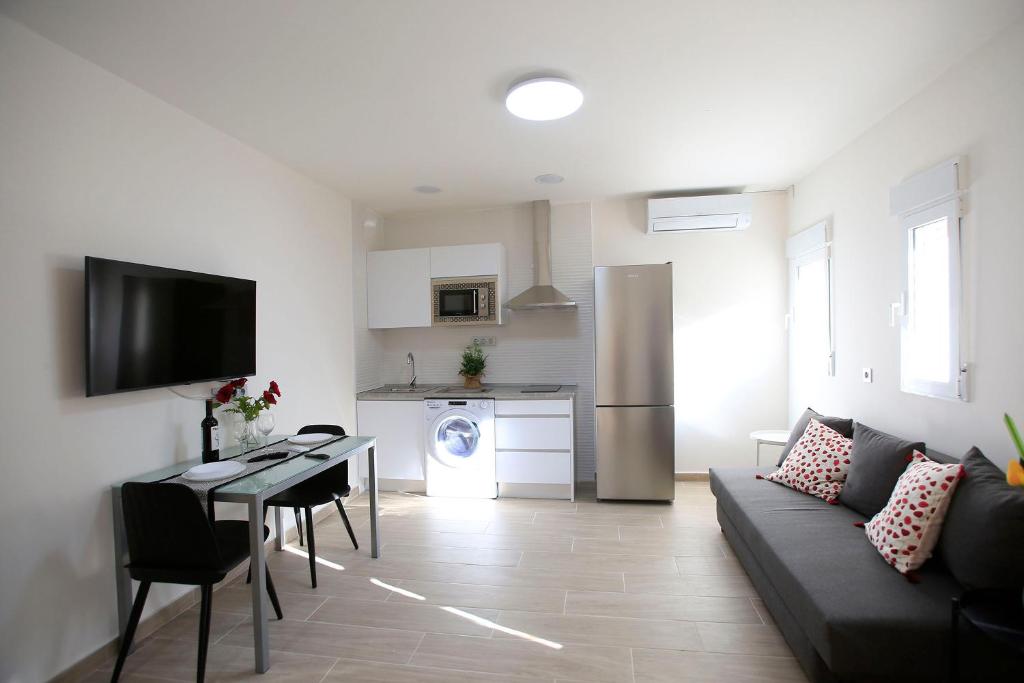 sala de estar con sofá, mesa y cocina en Apartamentos Amanecer Centro en Murcia