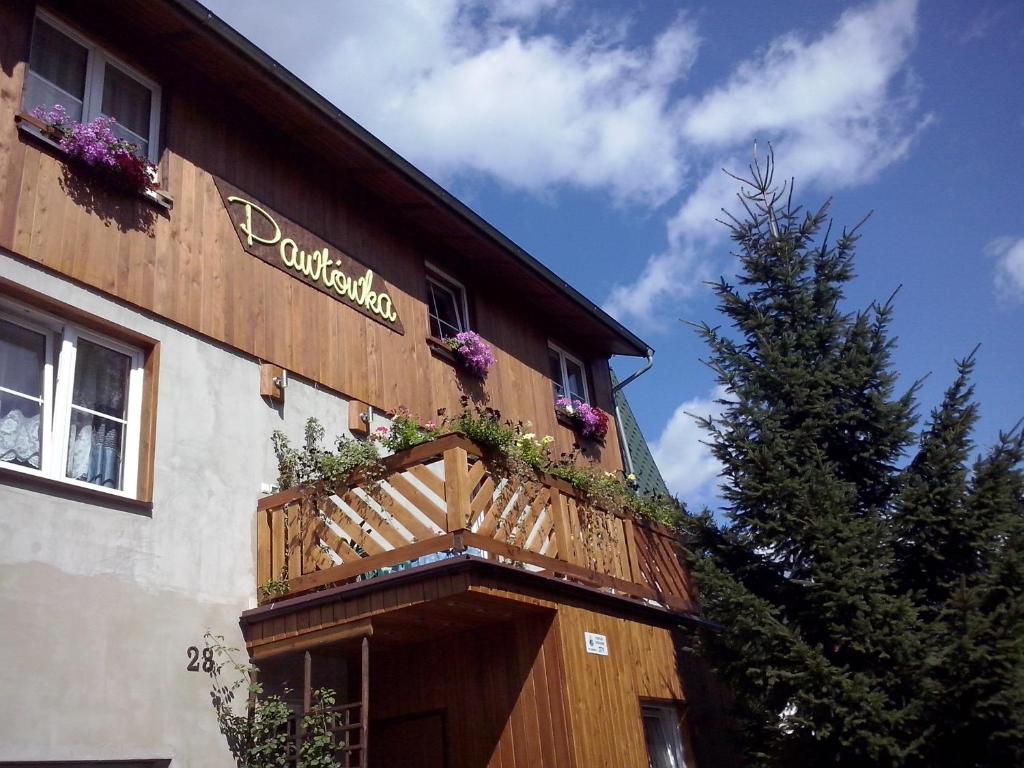 a building with a balcony with flowers on it at Pawłówka B&B in Szklarska Poręba