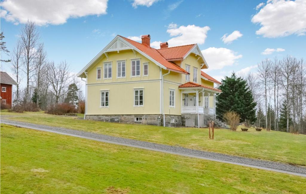 une maison jaune avec un toit rouge sur une pelouse dans l'établissement Beautiful Home In Juskog Husa With House A Panoramic View, à Navarsviken