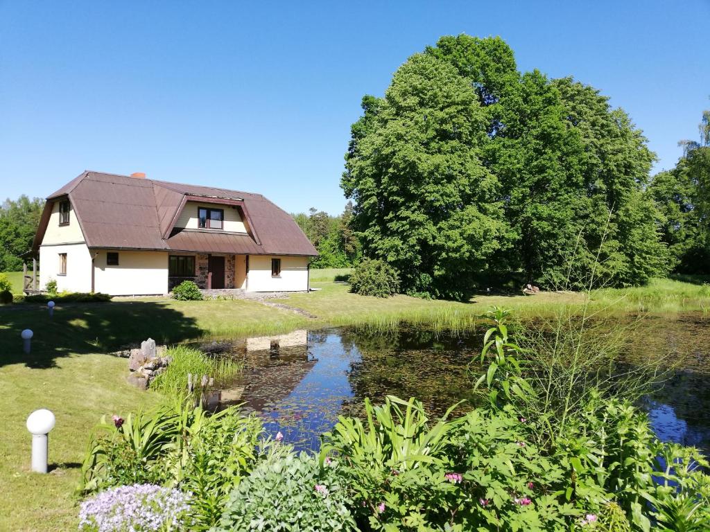 uma casa com um lago no quintal em Liepziedos em Ēdole