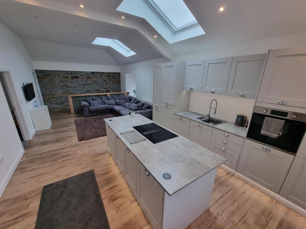 a kitchen with a kitchen island and a living room at Beautiful 2 bedroom home with private bar below in Ystradgynlais