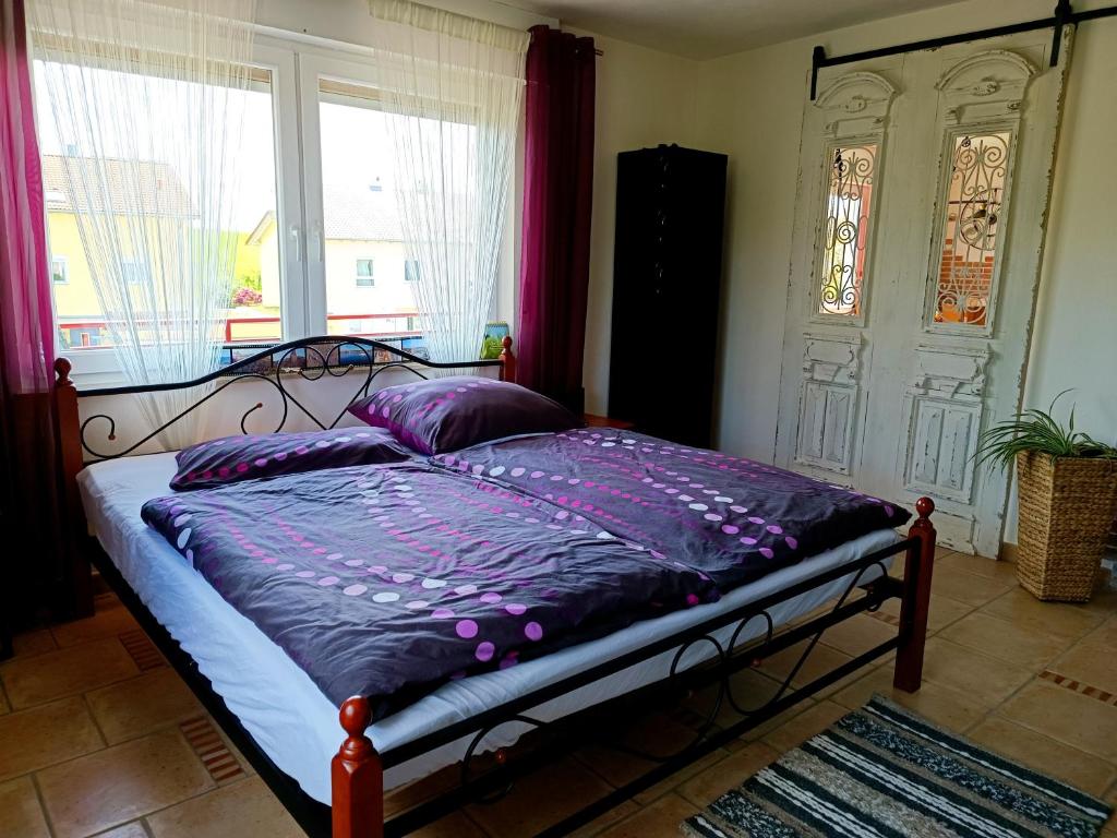 sypialnia z łóżkiem z fioletową pościelą i oknem w obiekcie Casa del Norte w mieście Brackenheim