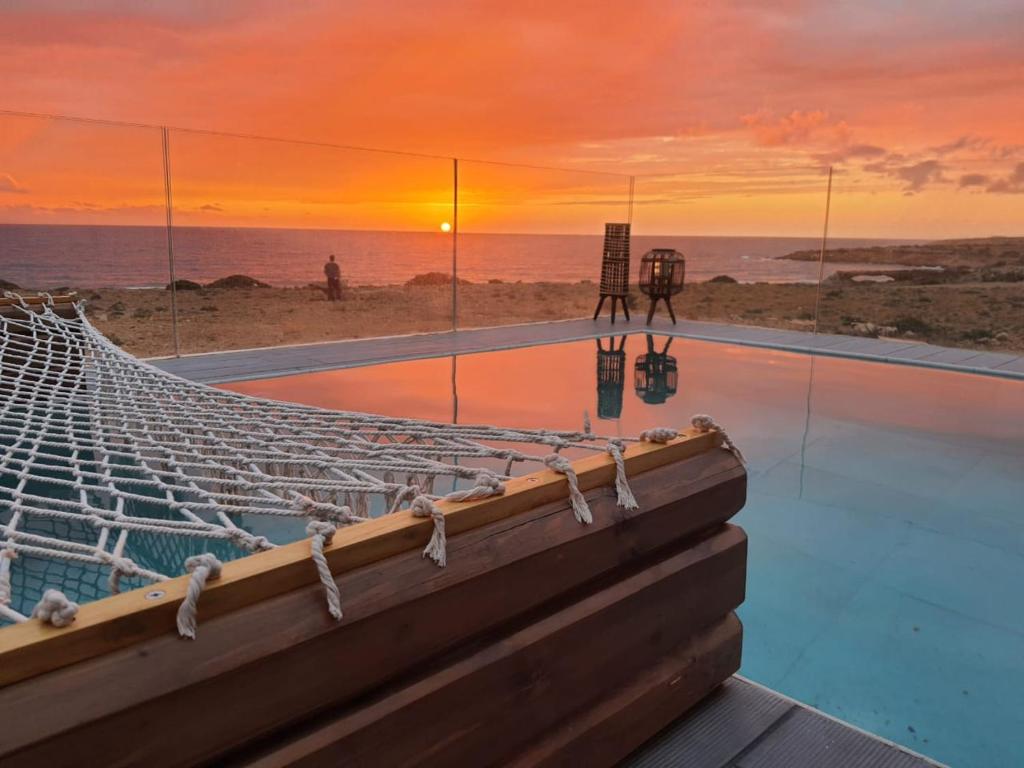 Tramonto Luxury Villa No2 - Breathtaking sunset view في كارباثوس: مسبح لا نهاية له مع إطلالة على المحيط عند غروب الشمس