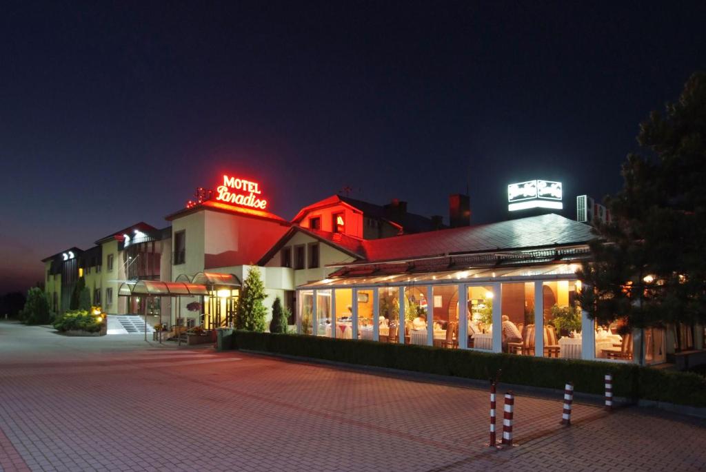 a building with a sign on top of it at night at Motel Paradise in Torzym