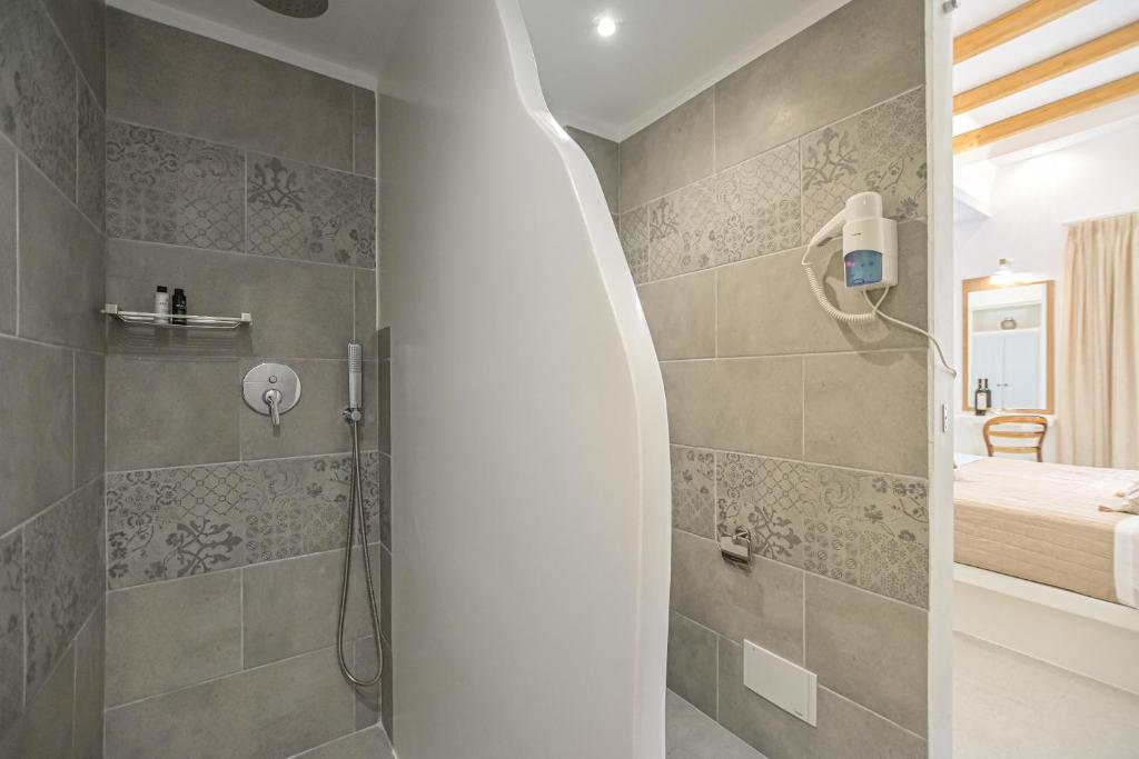 a bathroom with a walk in shower next to a bed at Elite Suites Naxos in Naxos Chora