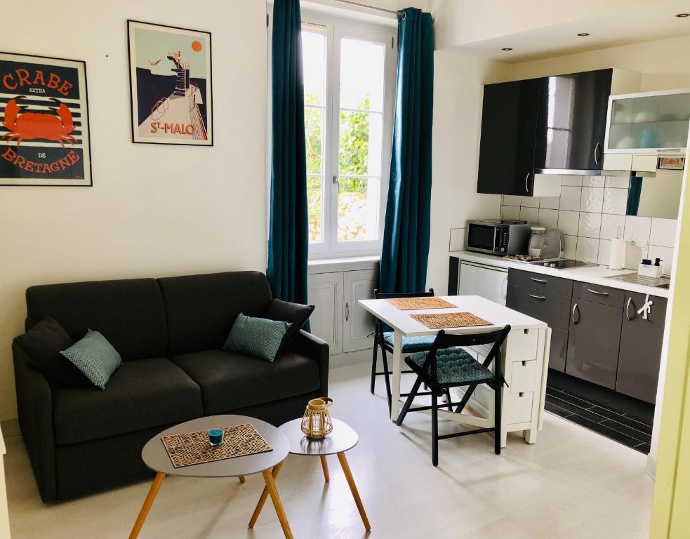 ein Wohnzimmer mit einem Sofa und einem Tisch in der Unterkunft Studio lumineux Saint-Ideuc à 1km de la plage in Saint-Malo