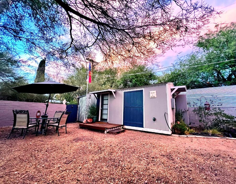 a small shed with a table and chairs and an umbrella at Peaceful Tucson Tiny House Getaway with Backyard in Tucson