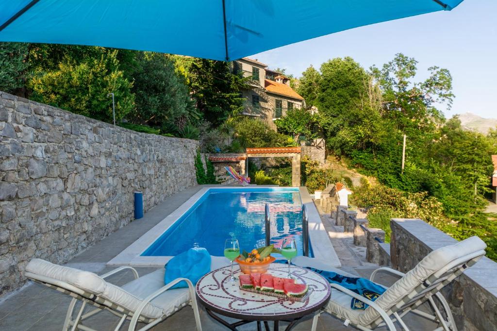 a pool with a table and chairs and an umbrella at Villa Blanka in Žrnovnica