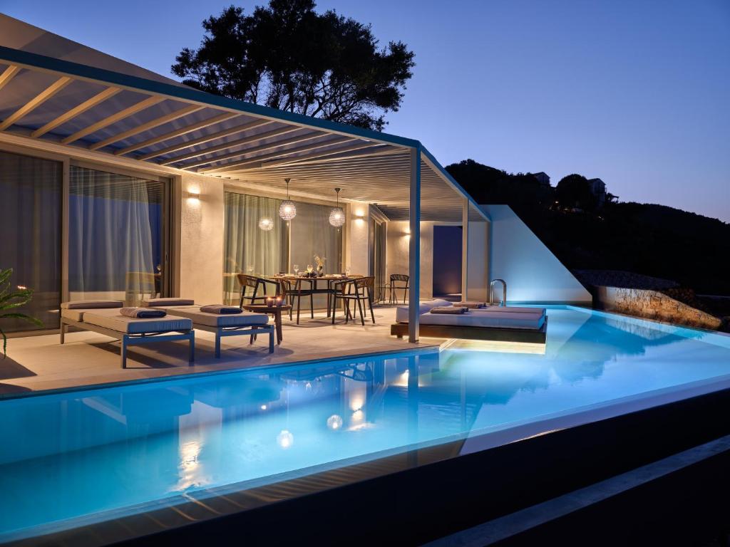 a villa with a swimming pool at night at Yoma Cove Suites in Volímai