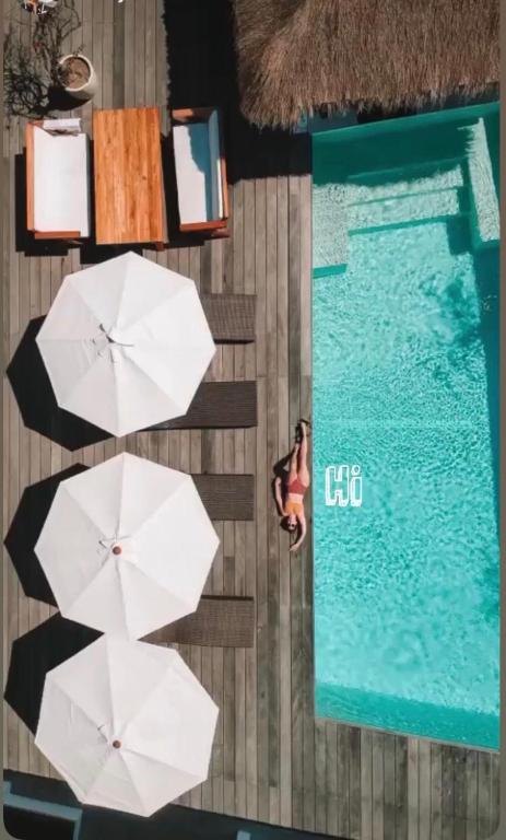 an overhead view of a pool with white umbrellas and a woman in at Motel LOVE SONG Canggu in Canggu