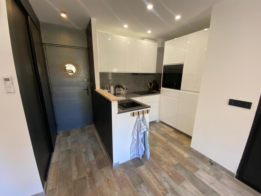 a kitchen with white cabinets and a wooden floor at appartement vue mer avec place de parking privée in Sainte-Maxime