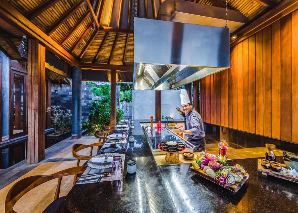a chef preparing food in a kitchen in a restaurant at Furaveri Maldives - COMPLIMENTARY ROUND-TRIP SEAPLANE TRANSFER for two for a minimum of 5 nights or more from May 1st to October 31st, 2025 in Raa Atoll