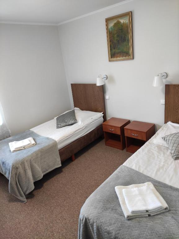 a hotel room with two beds and two tables at Hotel MAGNAT in Głogów Małopolski