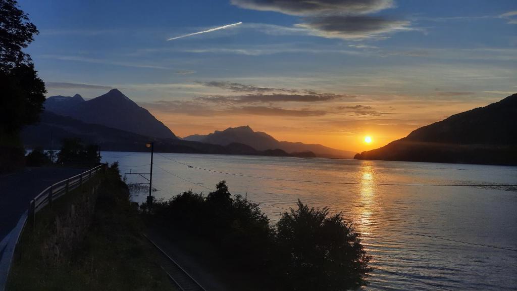 a sunset over a body of water with mountains at Lakeside Interlaken Jungfrau in Därligen