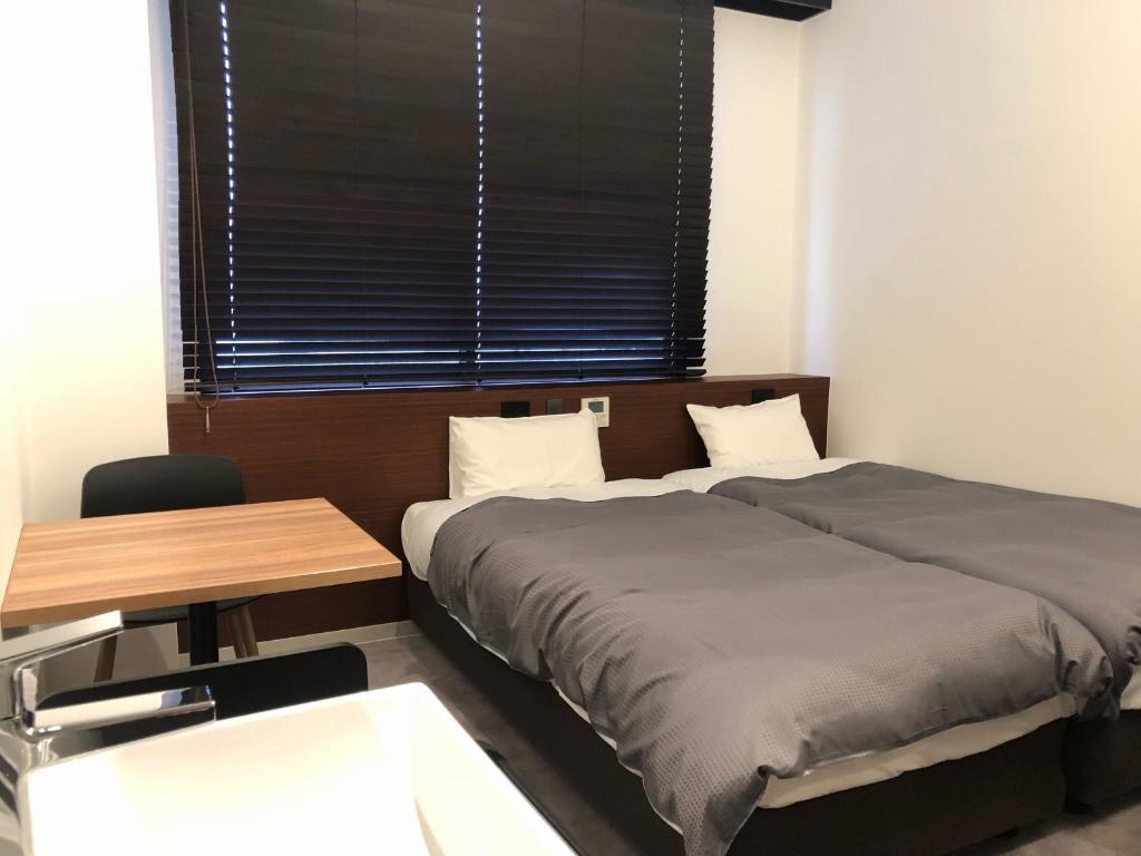 a bedroom with two beds and a table and a window at Hotel Sun Road in Amakusa