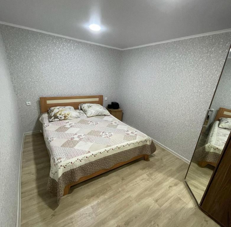 a bedroom with a bed and a mirror at Дачный домик 106 in Balqash