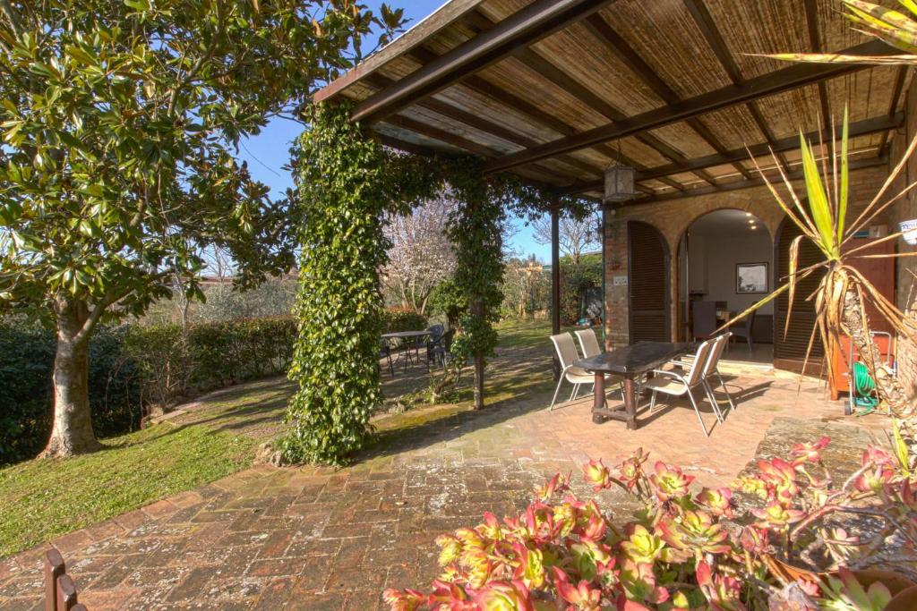 patio ze stołem i krzesłami pod pergolą w obiekcie Il giardino del giuggiolo w Sienie