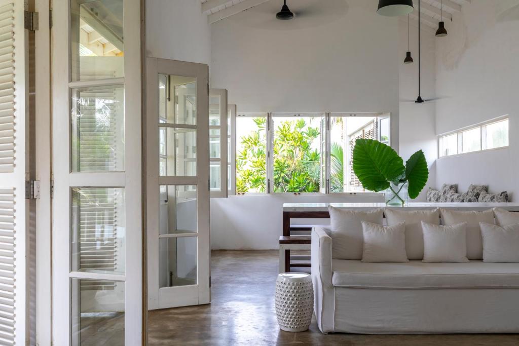a living room with a white couch and some windows at Arabella on Boossa in Galle