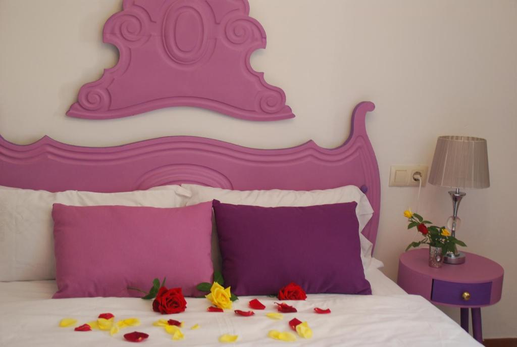 Una cama con almohadas moradas y moradas y flores. en Cal Sabater en Preixana