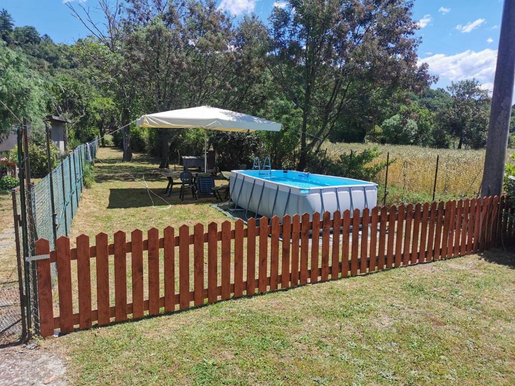 a fence with an umbrella and a swimming pool at Villa Olga - Lunigiana in Filattiera