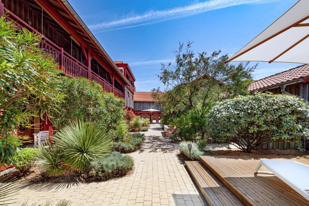 a walkway in front of a building with plants at Hotel de La Plage in Contis-les-Bains