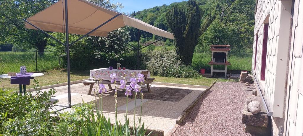 un patio con mesa y sombrilla en Ferme De La Grange Du Bas, en Saint-Bresson