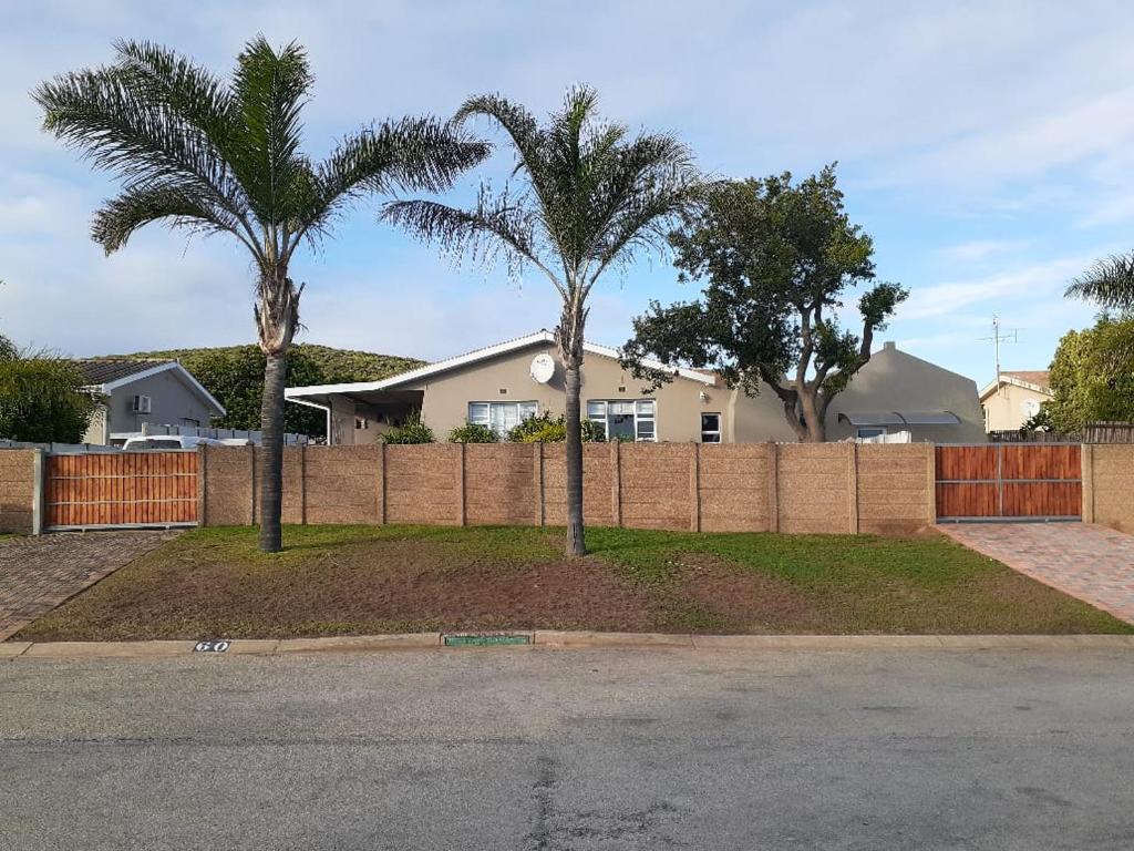 a fence with two palm trees in front of a house at SixtyB in Despatch