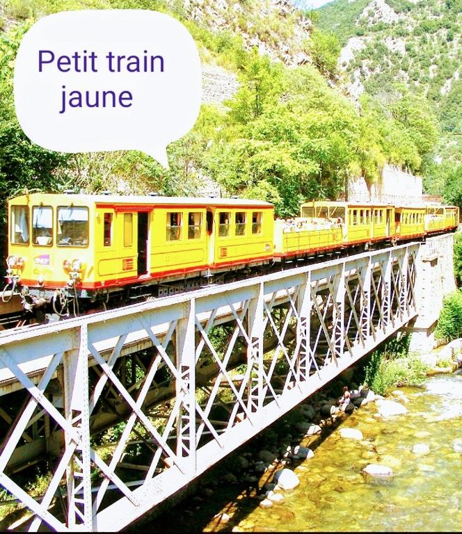 a yellow train on a bridge over a river at Superbe appartement neuf T3 6pers 45m2 in Font-Romeu-Odeillo-Via