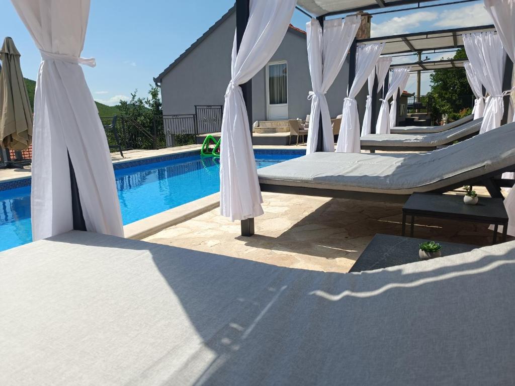 a group of beds in front of a pool at Villa Marija with heated pool in Trilj