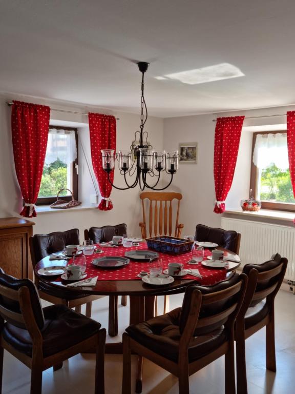 een eetkamer met een tafel en stoelen en rode gordijnen bij Ferienhaus Ritzmais in Bischofsmais