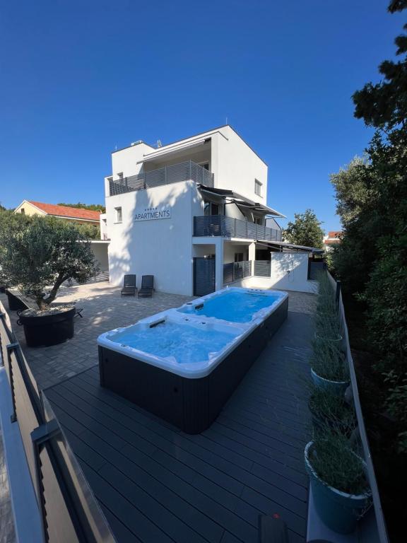 a house with a swimming pool on a deck at Apartmani Kumenat in Biograd na Moru