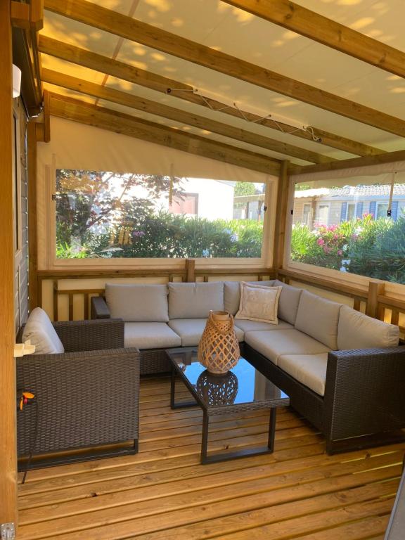 un porche cubierto con sofá y mesa en Mobil home de charme en Fréjus