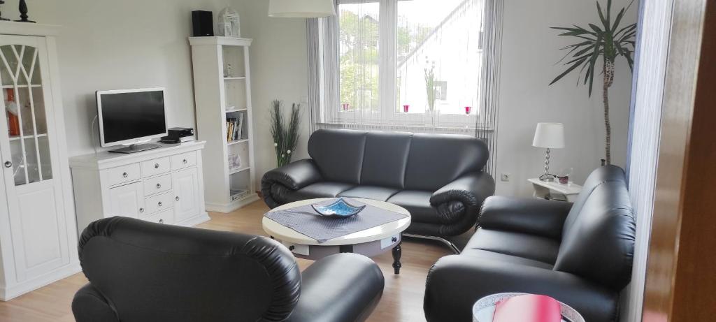 a living room with black leather chairs and a tv at Ferienwohnung Klötsch in Katzwinkel