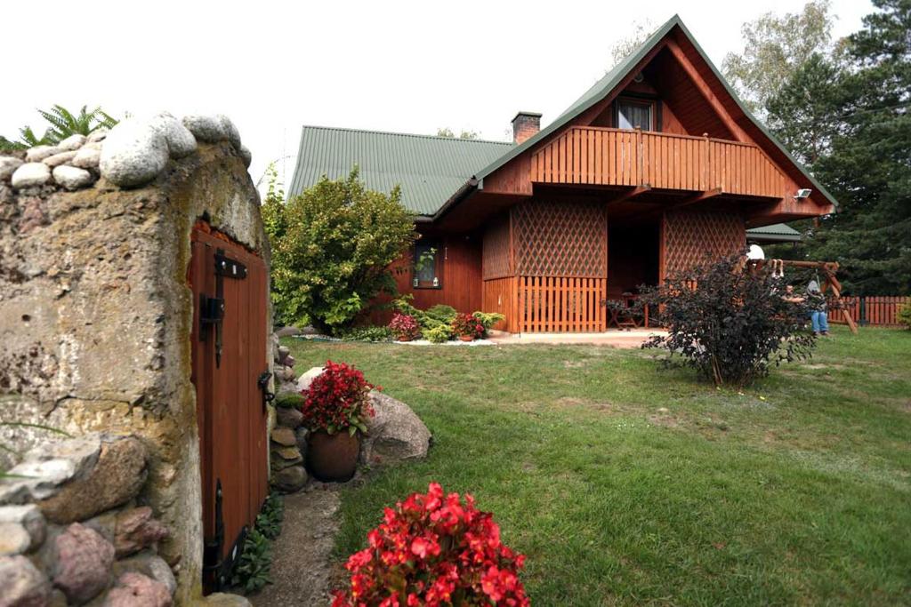 a house with a stone wall and a yard with flowers at Agroturystyka Nad Tanwią in Biszcza