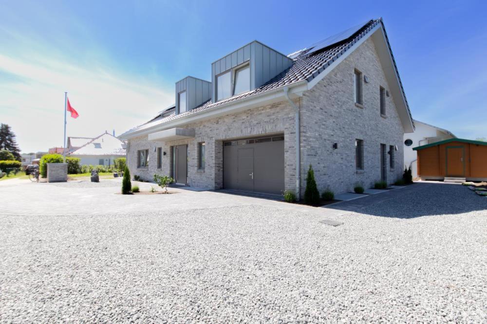 ein weißes Backsteinhaus mit Garage auf einer Auffahrt in der Unterkunft Ferienwohnung 4 Haus Meeresrauschen in Haffkrug in Haffkrug