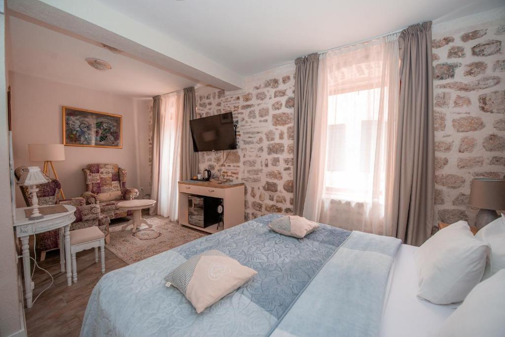 um quarto com uma cama, uma secretária e uma televisão em Antika Guesthouse em Kotor