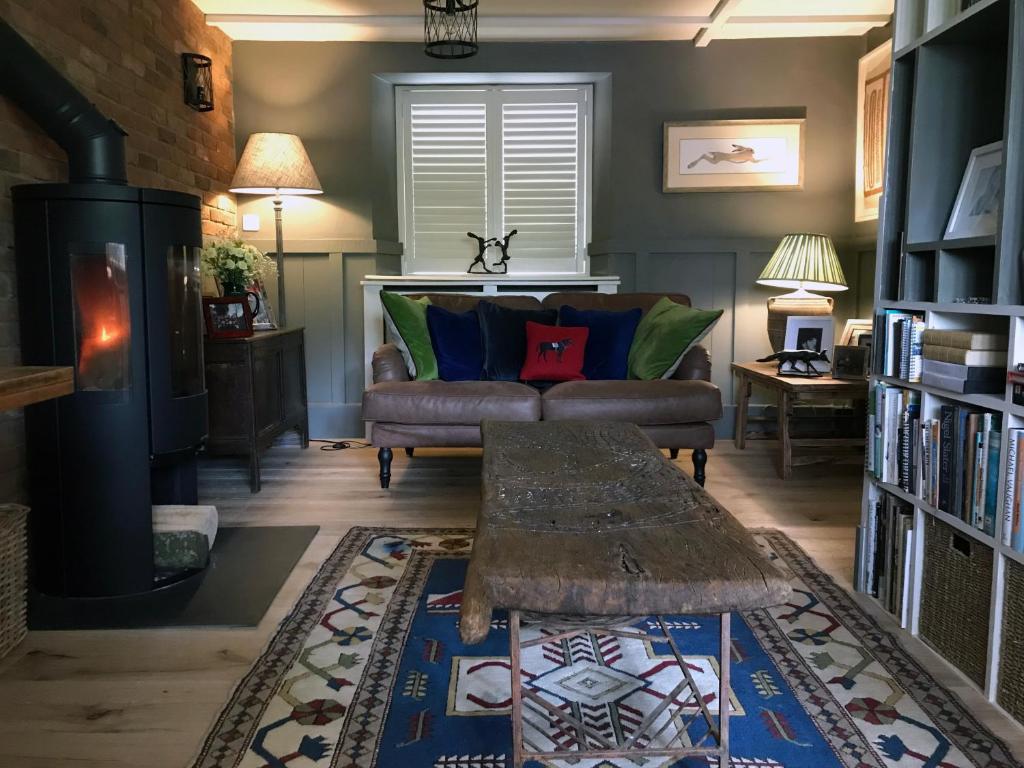 een woonkamer met een bank en een open haard bij Hornes Cottage in Longborough
